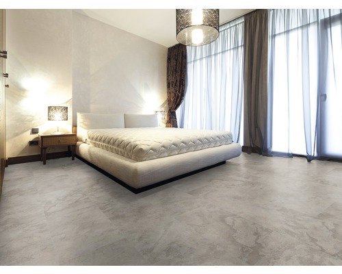 Schlafzimmer mit Bett, Nachttisch und Bodenbelag in Steinoptik