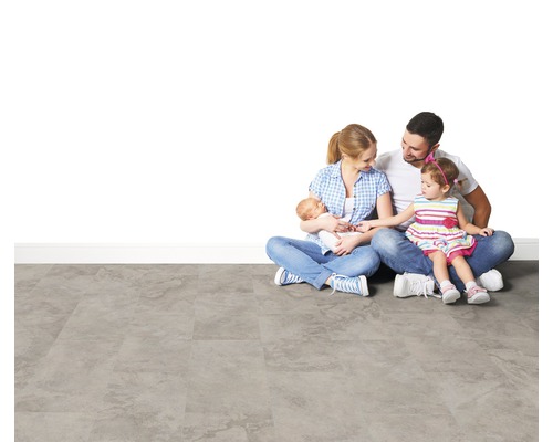 Eine Familie sitzt auf einem grauen Bodenbelag.