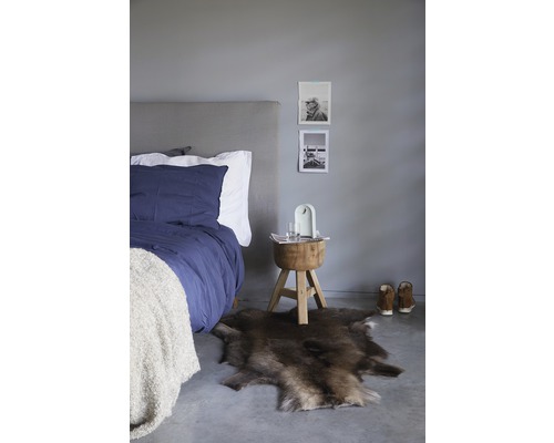 Schlafzimmer mit Bett, Fellteppich und Holzhocker