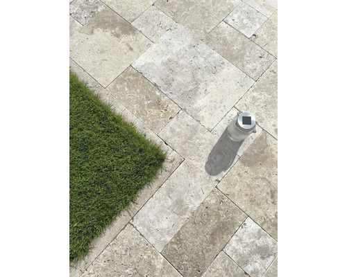 Verlegte Natursteinplatten im Außenbereich mit Rasenfläche und Solarleuchte