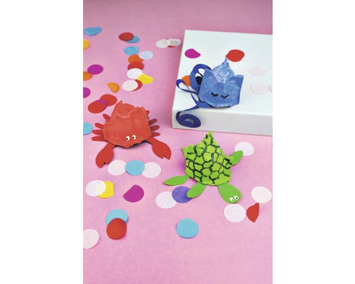 Szene mit einem roten Krebs, einer grünen Schildkröte und einem blauen Fisch aus Eierkartons gebastelt und Konfetti.