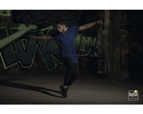 Mann tanzt vor einer Wand mit Graffiti. MagPaint Europe Logo.