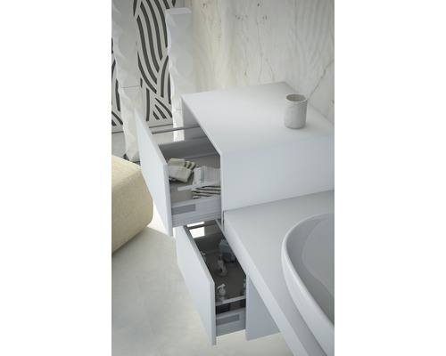 Detailaufnahme eines weißen Waschtischunterschranks mit zwei offenen Schubladen, die Handtücher und Pflegeprodukte zeigen.