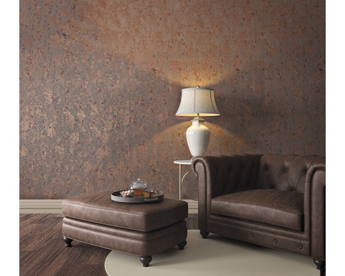 Wohnzimmer mit Chesterfield-Sessel, Ottomanen, Tischlampe und gemusterter Tapete für ein gemütliches Ambiente