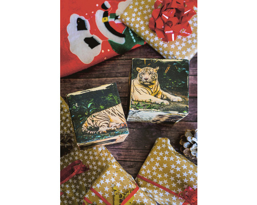 Dekorative Holzklötze mit Tigerbildern und Weihnachtspapier auf einem Holztisch