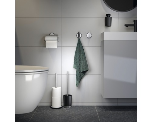 Badezimmeransicht mit Toilette, Waschbecken, Handtuch, Toilettenpapierhalter und Toilettenbürste