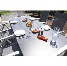 Gedeckter Gartentisch mit Stühlen, Geschirr, Gläsern, Speisen und Getränken für eine Mahlzeit im Freien.
