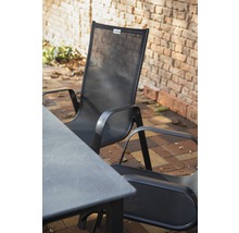 Gartentisch und Gartenstühle aus Metall und Textil vor einer Ziegelmauer