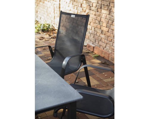 Gartentisch und Gartenstühle aus Metall und Textil vor einer Ziegelmauer