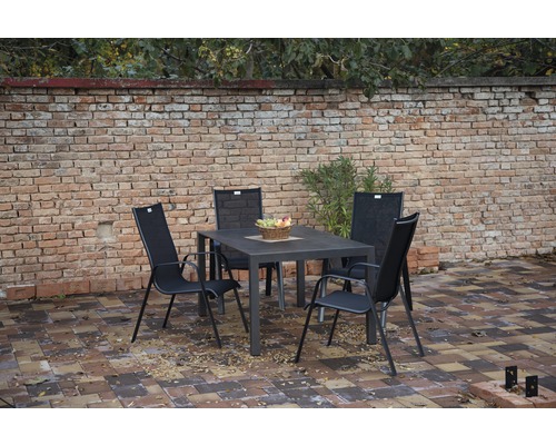 Gartensitzgruppe mit Tisch und vier Stühlen vor einer Ziegelmauer