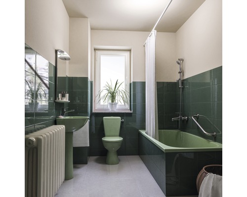 Badezimmer mit Badewanne, Waschbecken, Toilette, Heizkörper, Fenster und Pflanzen