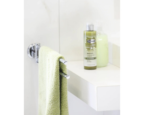 Handtuchhalter mit einem grünen Handtuch und Badezusätze auf einem Regal