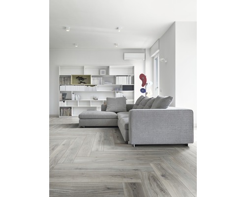 Heller Wohnraum mit grauem Ecksofa, Bücherregal und Parkettboden