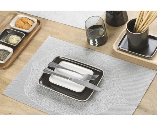 Tischdekoration mit Tellern, Besteck und Snacks auf Tischsets