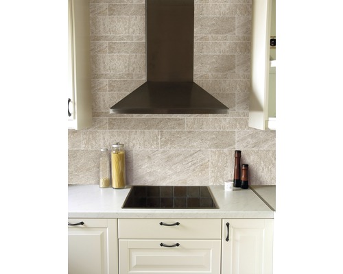 Küchenszene mit Dunstabzugshaube, Kochfeld, Fliesen und Küchenutensilien auf einer Arbeitsplatte.