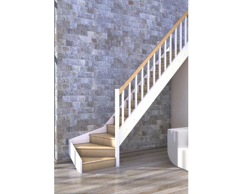 Treppe mit Holzstufen und weißem Geländer vor Steinwand