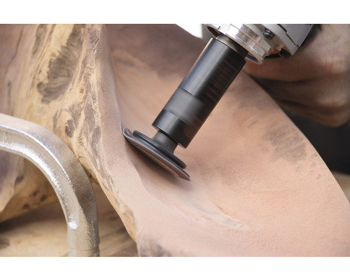 Detailansicht einer Schleifmaschine beim Bearbeiten eines Holzstücks.