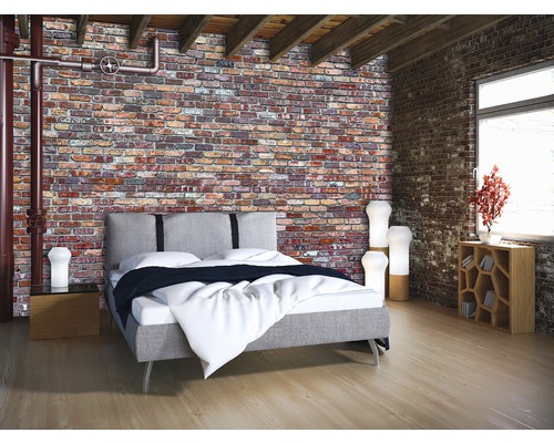 Schlafzimmer mit Bett vor einer Ziegelwand