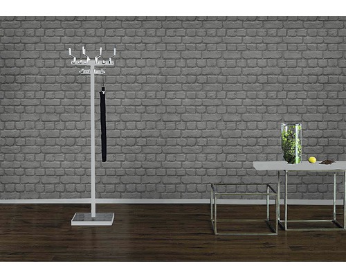 Flur mit Garderobenständer, Schirm und Tisch mit Dekoration vor einer Ziegelwand