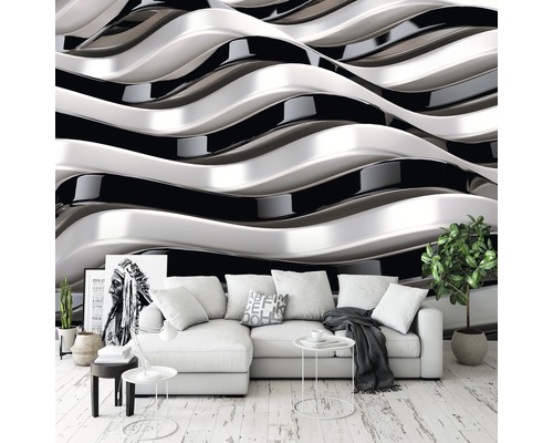 Wohnzimmer mit weißem Ecksofa vor einer Tapete mit schwarzem und silbernem Wellenmuster.