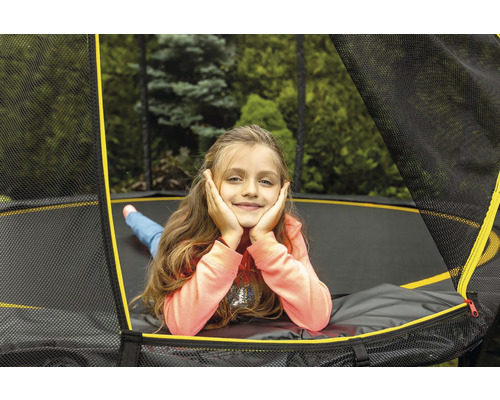 Mädchen liegt auf einem Trampolin mit Sicherheitsnetz