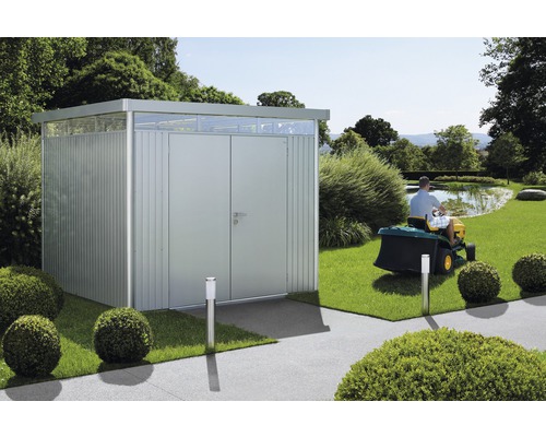 Gartenschuppen aus Metall mit Doppeltür und Oberlicht in einem Garten mit Rasentraktor