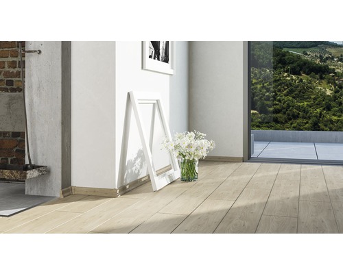 Heller Raum mit Laminatboden in Holzoptik, Fußleisten, Bilderrahmen und Blumen