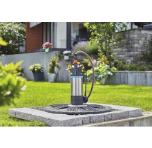 Gartenszene mit einer Gardena Tauchdruckpumpe auf einem Steinplatz, die Wasser ableitet