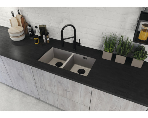 Doppelspülbecken in einer Küchenarbeitsplatte mit Armatur und diversen Küchenutensilien.
