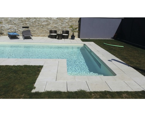 Swimmingpool mit hellen Steinfliesen und Gartenmöbeln