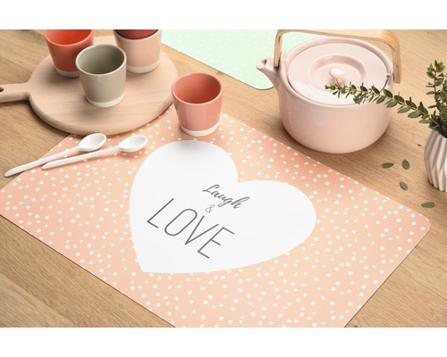 Tischdekoration mit Tellern, Tassen, Teekanne und Tischset mit der Aufschrift Laugh & Love