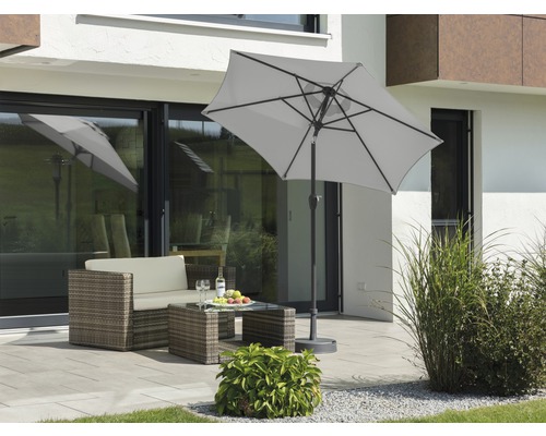 Szene mit einem Sonnenschirm, einer Loungegarnitur und einem Gartentisch auf einer Terrasse.