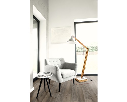Helles Zimmer mit Sessel, Stehlampe und kleinem Beistelltisch auf Laminatboden.