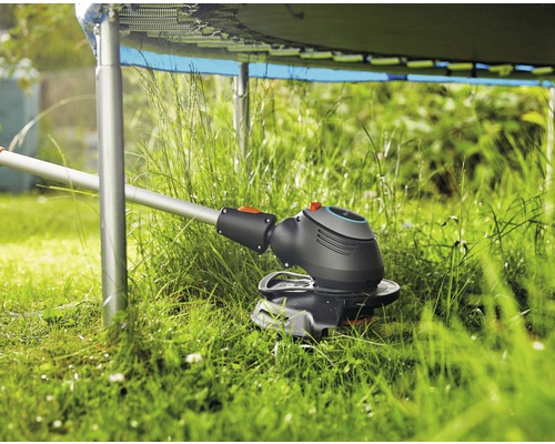 Rasentrimmer im Einsatz unter einem Trampolin im Garten.