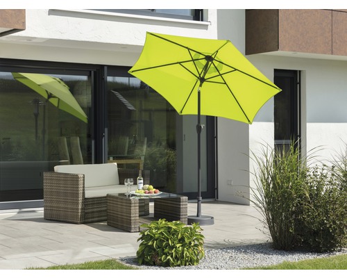 Szene mit gelbem Sonnenschirm, Rattansitzgruppe und Tisch auf einer Terrasse