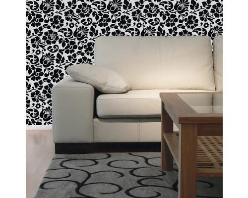Wohnzimmer mit Sofa, Holztisch, gemustertem Teppich und floraler Tapete