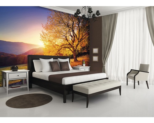 Schlafzimmer mit Bett, Nachttischen und Fototapete mit Baum im Sonnenlicht