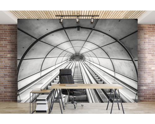 Fototapete mit Schwarzweiß-Motiv einer Rolltreppe in einem Tunnel, angebracht in einem Raum mit Schreibtisch und Bürostuhl.