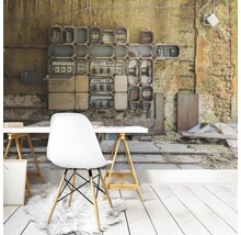 Wohnraum mit Fototapete, die eine alte Schalttafel und eine baufällige Wand darstellt, dazu ein weißer Schreibtisch und ein Stuhl.