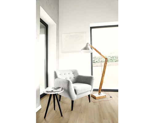 Heller Wohnraum mit Sessel, Stehlampe und kleinem Tisch auf Holzboden