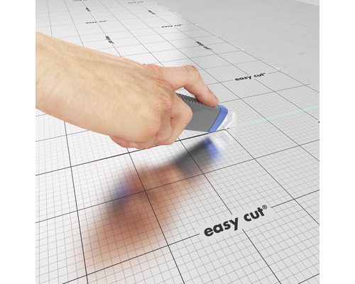 Hand schneidet mit einem Teppichmesser auf einer Schneidematte mit Raster