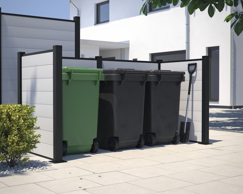 Mülltonnenbox mit drei Mülltonnen und einem Spaten vor einem Haus