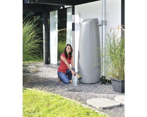 Frau befüllt eine Gießkanne an einem Regenwassertank im Garten