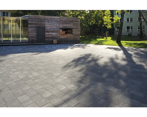 Grauer Pflasterbelag vor einem Gebäude mit der Aufschrift Campus Office.