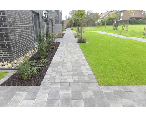 Gepflasterter Weg durch einen Garten mit Rasenflächen