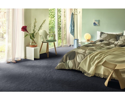 Schlafzimmer mit Bett, Stuhl und dunklem Teppichboden.
