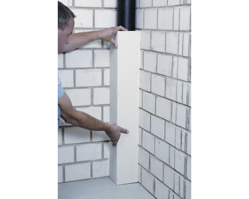 Mann montiert eine Eckleiste an einer gemauerten Wand.