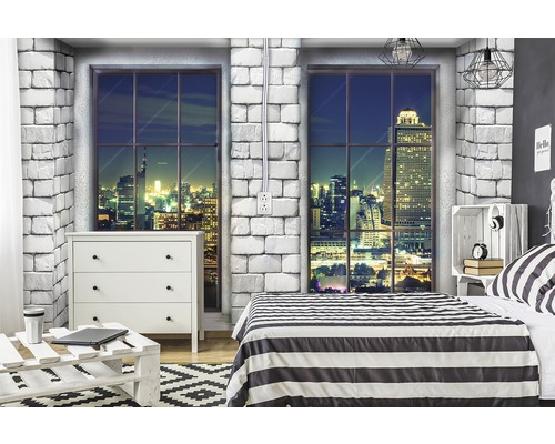 Schlafzimmer mit Kommode, Bett und Fenster mit Stadtblick bei Nacht