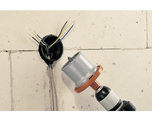 Bohrmaschine mit Bohrkrone bohrt Loch in Wand für Elektroleitung