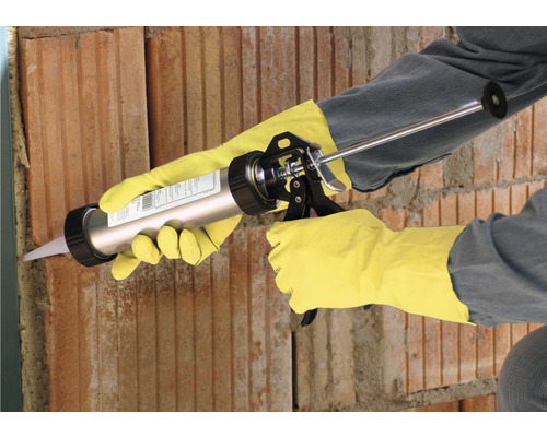 Handwerker benutzt eine Kartuschenpistole an einer Ziegelwand